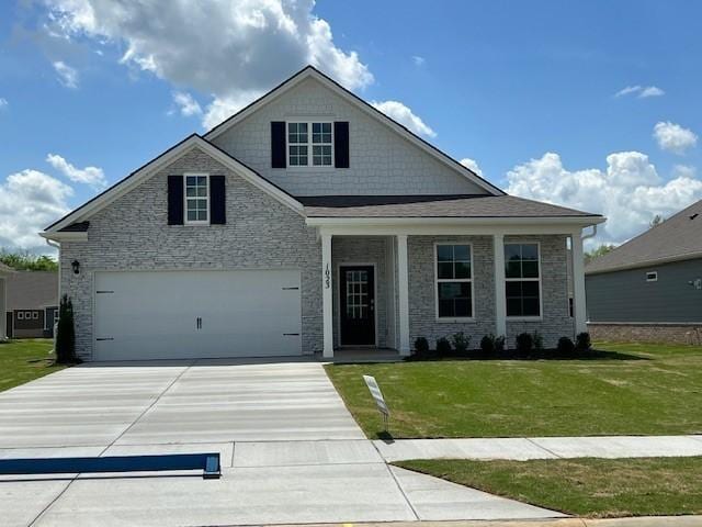 view of front of house with a porch, an attached garage, stone siding, driveway, and a front yard