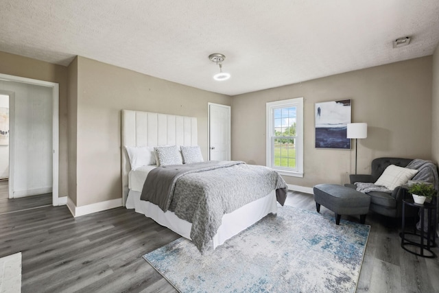 bedroom with a textured ceiling, baseboards, and wood finished floors