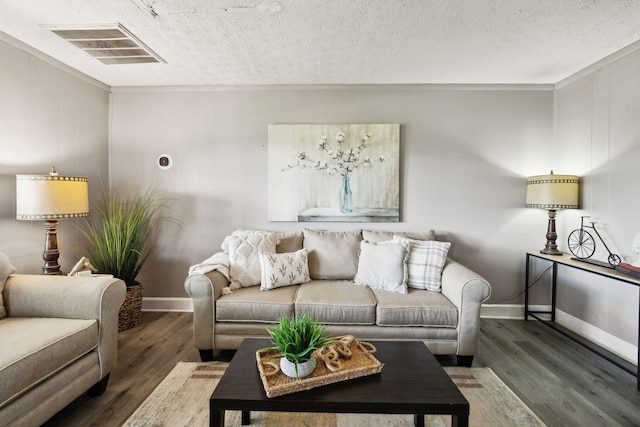 living area with a textured ceiling, visible vents, wood finished floors, and baseboards