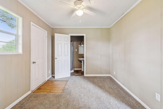 unfurnished bedroom with carpet, a textured ceiling, baseboards, and crown molding