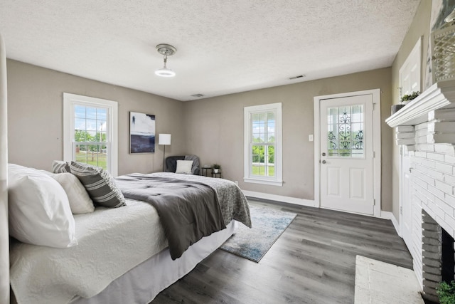 bedroom with a textured ceiling, baseboards, visible vents, wood finished floors, and a fireplace