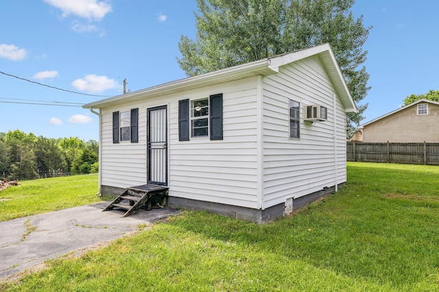 view of outbuilding featuring a wall mounted AC, entry steps, and fence