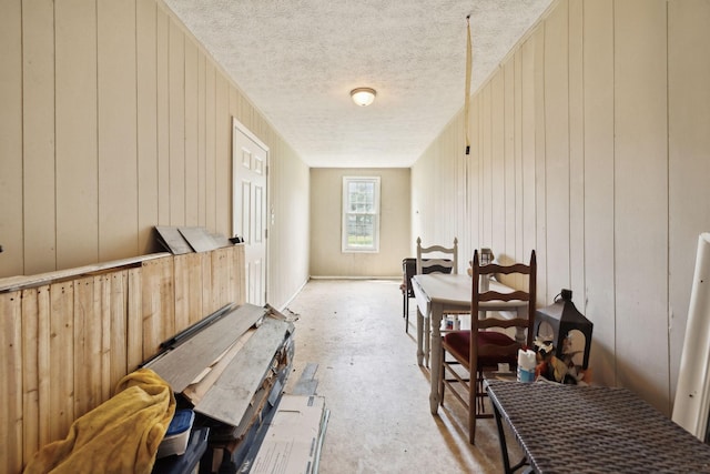 interior space with wooden walls, a textured ceiling, and concrete floors