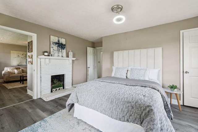 bedroom featuring a fireplace, baseboards, and wood finished floors