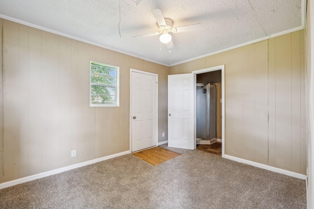 unfurnished bedroom featuring ornamental molding, a textured ceiling, carpet floors, a ceiling fan, and baseboards