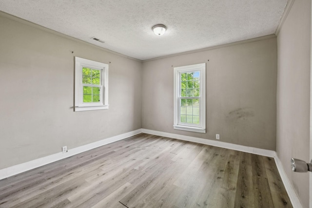 empty room with baseboards, crown molding, a textured ceiling, and wood finished floors