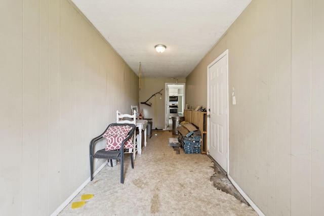 hallway featuring wooden walls and carpet