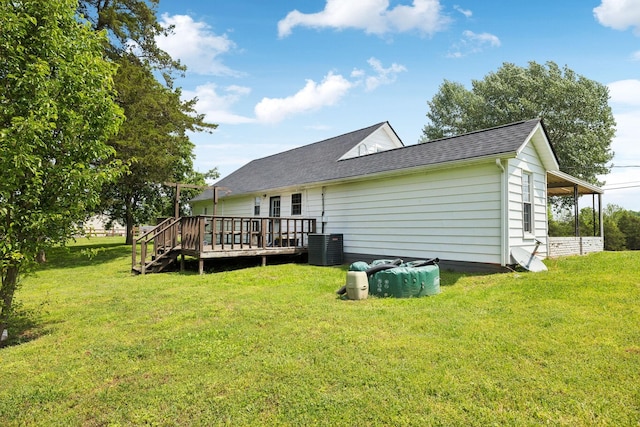 rear view of property with a wooden deck, a shingled roof, central AC, and a lawn