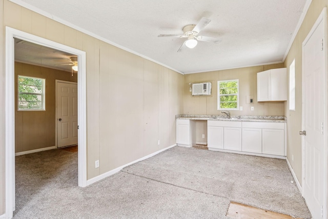 kitchen featuring white cabinets, crown molding, a wall mounted AC, and ceiling fan
