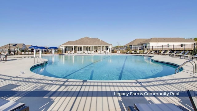 community pool with a patio area and fence