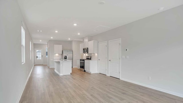 unfurnished living room with a sink, baseboards, light wood-type flooring, and recessed lighting