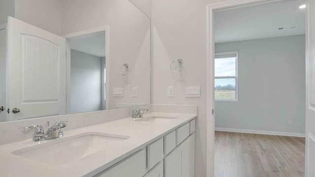 full bath featuring double vanity, wood finished floors, baseboards, and a sink