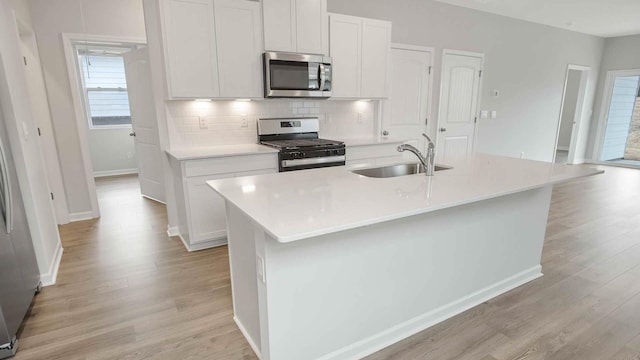kitchen featuring light wood finished floors, appliances with stainless steel finishes, tasteful backsplash, and a sink