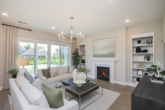 5963 Hunt Valley Dr, Spring Hill, TN 37174 - living area featuring built in features, a chandelier, a glass covered fireplace, dark wood finished floors, and baseboards