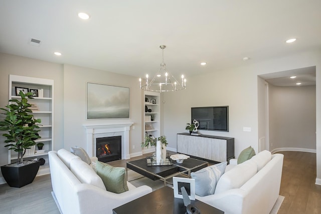 5963 Hunt Valley Dr, Spring Hill, TN 37174 - living area featuring wood finished floors, a chandelier, built in features, recessed lighting, and a glass covered fireplace