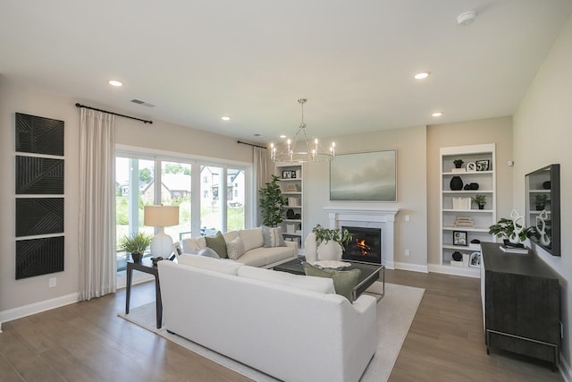 5963 Hunt Valley Dr, Spring Hill, TN 37174 - living area featuring dark wood-type flooring, built in features, a chandelier, a glass covered fireplace, and recessed lighting