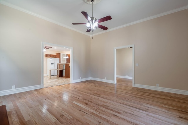 spare room featuring light wood finished floors, ornamental molding, baseboards, and ceiling fan