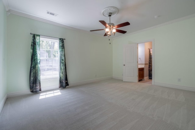 spare room with light colored carpet, ornamental molding, and a ceiling fan