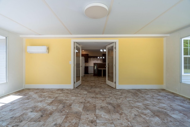 unfurnished room with an AC wall unit and baseboards