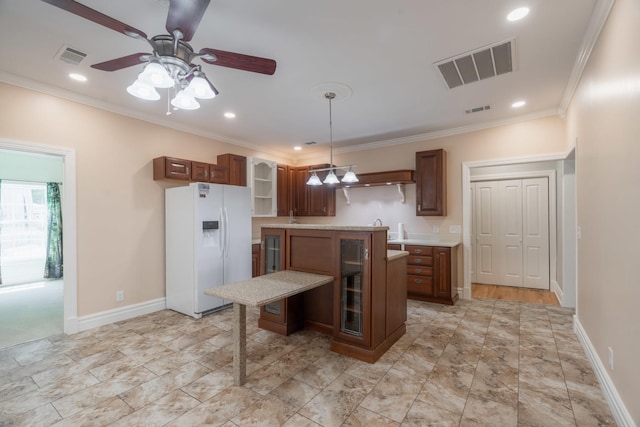 kitchen featuring ornamental molding, white fridge with ice dispenser, visible vents, ceiling fan, and a center island
