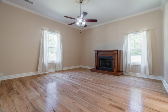 unfurnished living room featuring a fireplace with raised hearth, light wood-style flooring, crown molding, and plenty of natural light