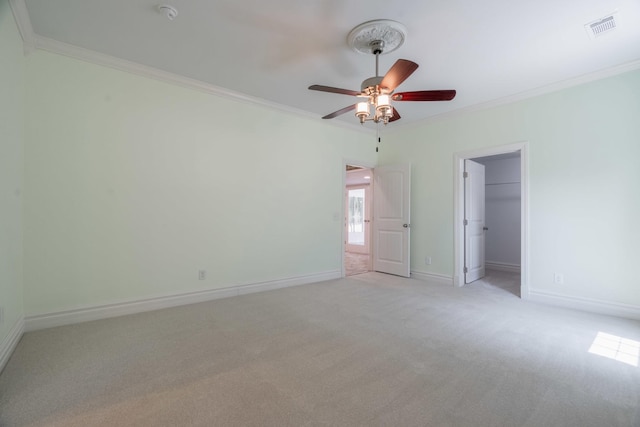 unfurnished bedroom with baseboards, visible vents, crown molding, a spacious closet, and light carpet