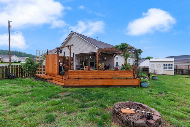rear view of house featuring a storage shed, a wooden deck, a lawn, an outdoor structure, and a fenced backyard