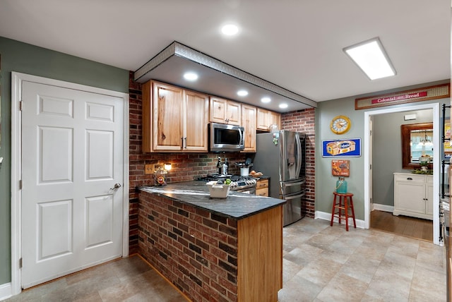 kitchen featuring a peninsula, recessed lighting, baseboards, dark countertops, and appliances with stainless steel finishes