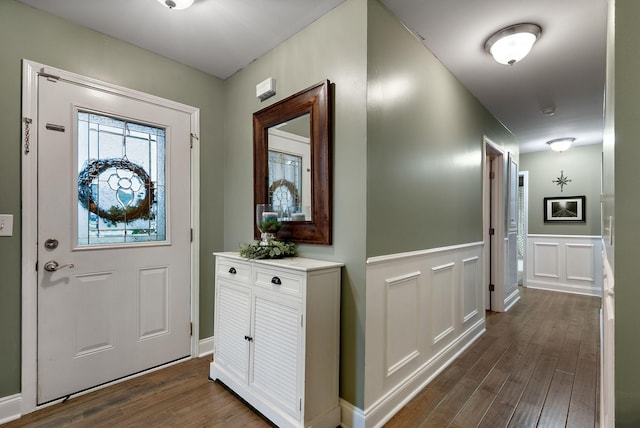 foyer with a decorative wall, a wainscoted wall, and dark wood-style flooring