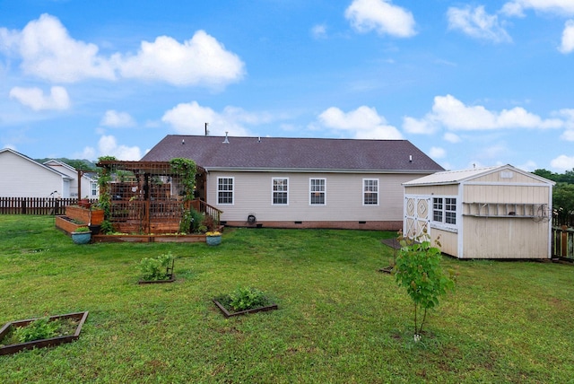 back of house featuring fence, crawl space, a storage unit, an outbuilding, and a vegetable garden