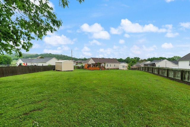 view of yard with an outbuilding, a residential view, a fenced backyard, and a storage unit