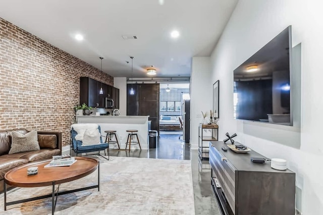 210 30th Ave N Unit 207, Nashville, TN 37203 - living room with brick wall, finished concrete floors, visible vents, and recessed lighting