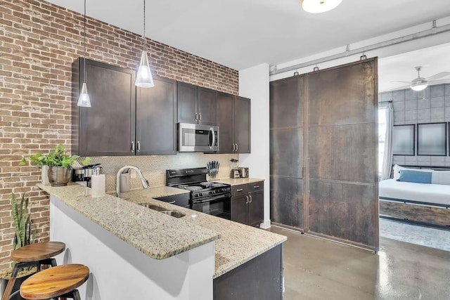 210 30th Ave N Unit 207, Nashville, TN 37203 - kitchen featuring black gas range, light stone counters, stainless steel microwave, and a sink