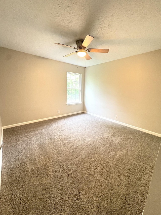 carpeted empty room with ceiling fan, a textured ceiling, and baseboards