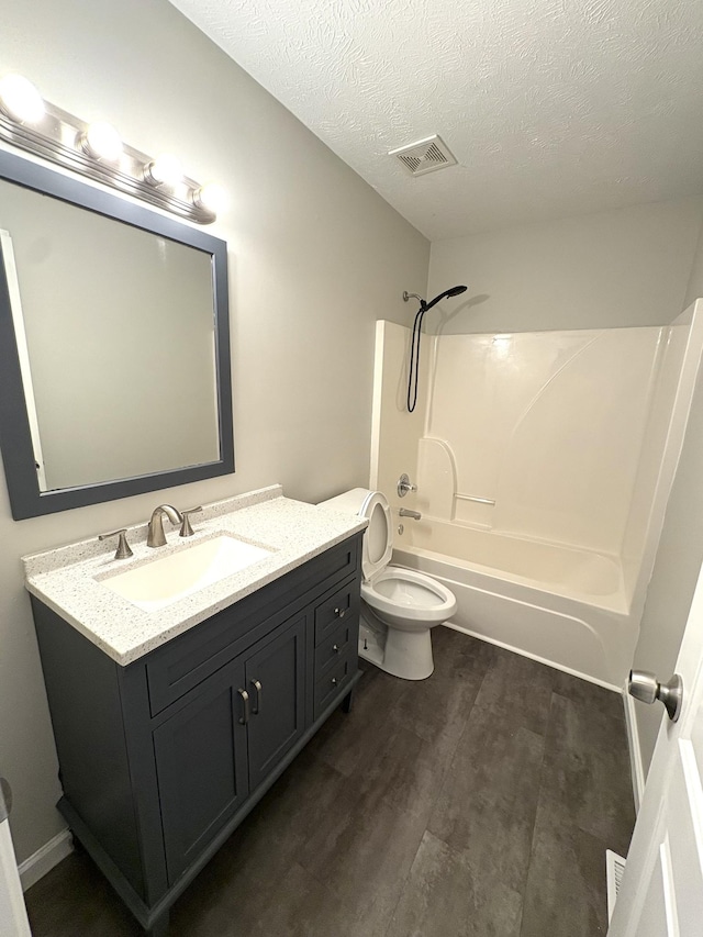 full bath featuring shower / bath combination, vanity, wood finished floors, toilet, and a textured ceiling