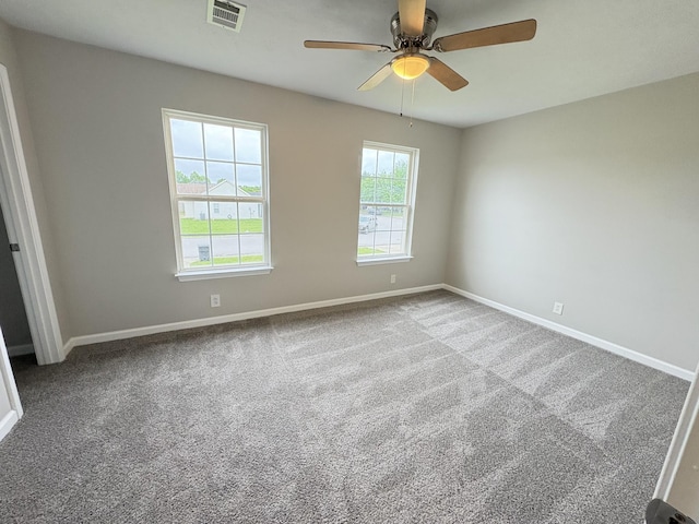 carpeted spare room featuring a ceiling fan and baseboards