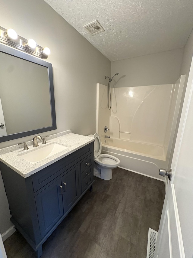 full bath with bathtub / shower combination, vanity, toilet, wood finished floors, and a textured ceiling