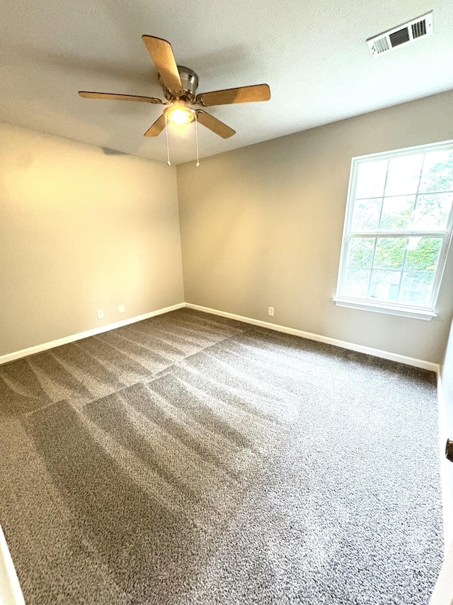 carpeted empty room featuring a ceiling fan and baseboards