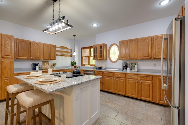 kitchen featuring glass insert cabinets, a breakfast bar, freestanding refrigerator, a kitchen island, and black electric stovetop
