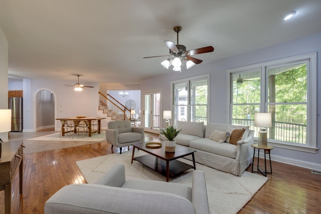 living area with baseboards, a healthy amount of sunlight, and ceiling fan with notable chandelier