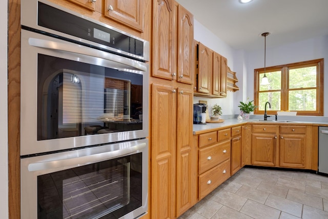 kitchen with light countertops, appliances with stainless steel finishes, pendant lighting, and a sink