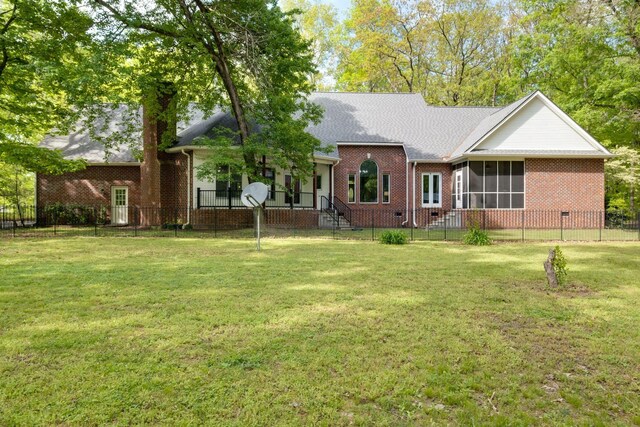 view of front of property with brick siding, a front yard, fence private yard, a chimney, and a sunroom