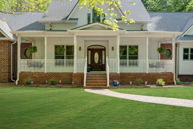 view of front of property featuring covered porch, roof with shingles, and a front yard
