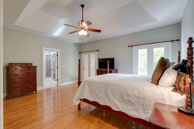 bedroom featuring baseboards, a raised ceiling, a ceiling fan, and wood finished floors