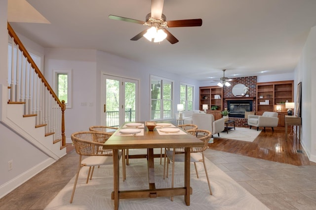 dining space with a fireplace, ceiling fan, baseboards, and a healthy amount of sunlight