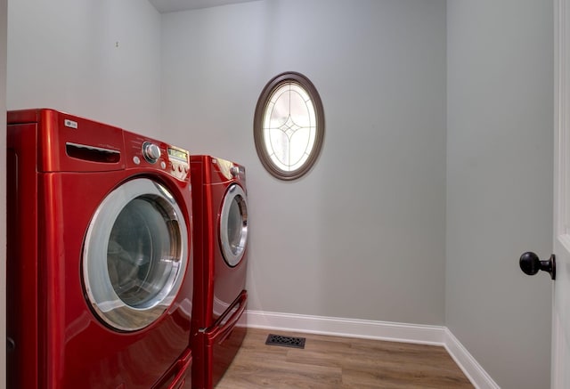 laundry area featuring baseboards, washer and dryer, visible vents, wood finished floors, and laundry area