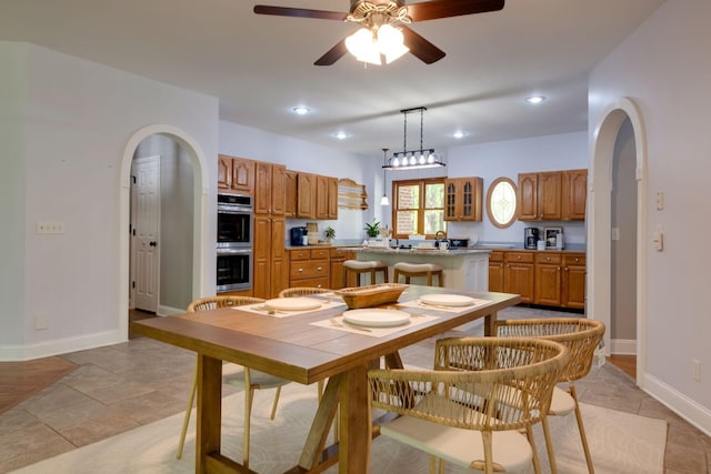 dining room featuring ceiling fan, baseboards, arched walkways, and recessed lighting