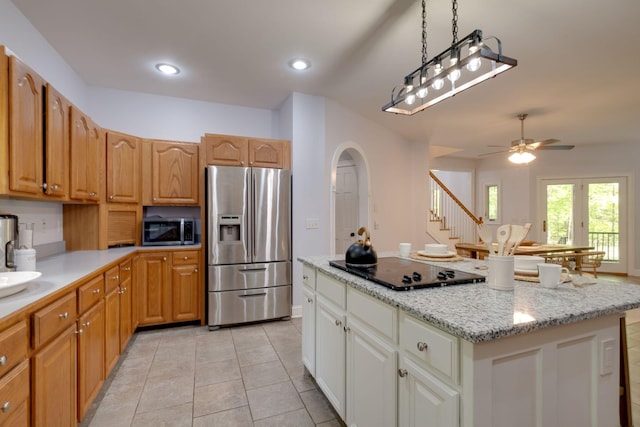 kitchen featuring light tile patterned floors, a center island, stainless steel appliances, pendant lighting, and light stone countertops