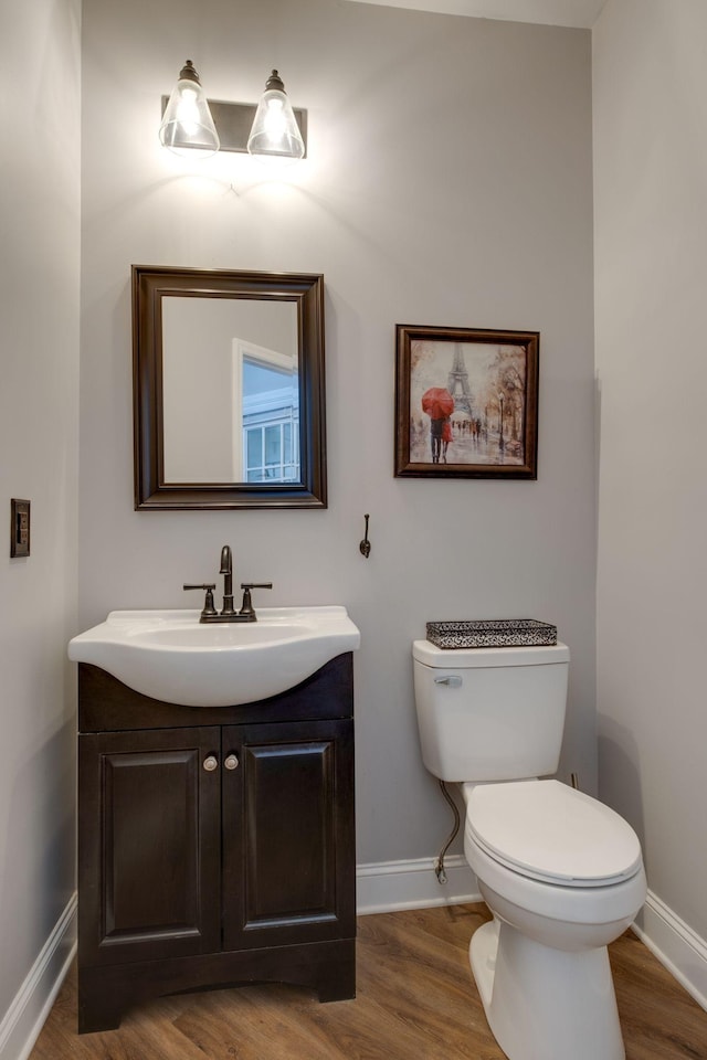 bathroom featuring vanity, toilet, baseboards, and wood finished floors