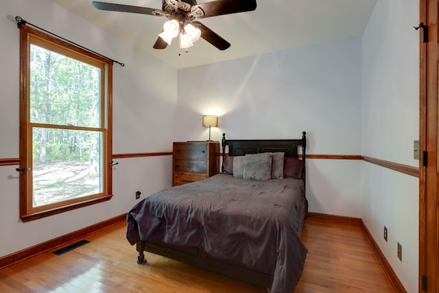 bedroom featuring wood finished floors, visible vents, and multiple windows